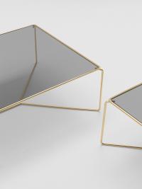 Particolare dei tavolini Proust che abbinano alla struttura in metallo ottonato il piano in vetro fumé