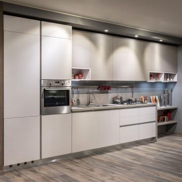 Cucina da 360 cm di larghezza con ante a gola, frigo incassato, colonna con forno, lavello filotop e fuochi in acciaio, pensili e cappa integrata