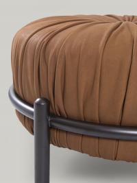 Detail of the upholstered part with pleated work contrasting with the metal frame