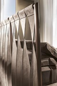 Detail of the metal frame headboard with curled leather straps 