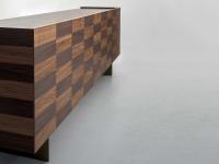 L'ipnotico disegno superficiale del legno intarsiato delinea le sezioni delle ante e dei cassetti
