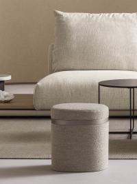 Pouf contenitore con vassoio Coffer nella versione in tessuto posizionato fronte divano in un living elegante e moderno