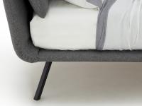 Detail of the minimalist bed frame and the tilted high feet in black matt metal