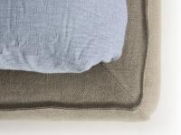 Detail of the upholstered bed frame covered in natural fabric with protruding seams