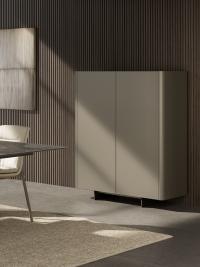 Three-quarter view of Maia modern cupboard with metal feet; top and doors in Titanium painted lacquer.