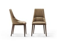 View from the front and side of the Lora upholstered chair with stitching and wooden legs. Leather upholstery and solid-wood base in the Canaletto Walnut finish.