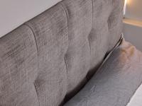 Detail of the headboard upholstered in taupe Nuvole fabric