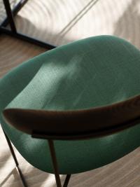 Detail of the upholstered seat covered in emerald green fabric