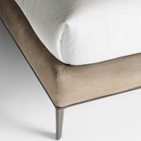 The delicate contrast between the upholstered bed frame and the metal base with legs