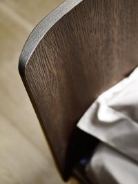 Detail of the wooden headboard, slightly bent on the sides finished in heat-treated oak
