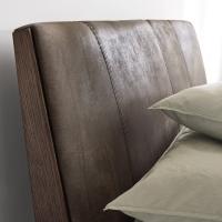 Detail of the upholstered headboard covered in vintage leather with hand-made stitching