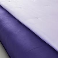 Detail of bed sheet set and satin bedspread with hue of lilac and purple