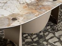Detail of the Patagonia ceramic top and base support feet in brass finish of the Indigo oval table