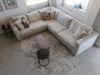 Light fabric corner sofa with decorative cushions.