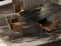 Gepolsterte Stühle mit Kissen ohne Armlehnen Dalila und Tisch Hidalgo. Bezug in Leder und freitragendem Cantileverfuß in Metall gestrichen Titanio.