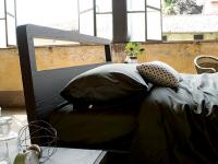 Minimalistisches Bett mit Feeling-Holzrahmen. Leicht geneigtes Kopf- und Fußteil im Verhältnis zum Lattenrost verleihen der Ergänzung Dynamik.