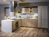 Graue L-Küche in Zementoptik mit sichtbaren Wänden und Regalen, Deckenabzugshaube, Kühlschrank und ausziehbarem Vorratsschrank