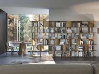Modulares Bücherregal Caravel, vorgeschlagen als Wandelement in einem Wohnzimmer mit passendem Holztisch und Stühlen