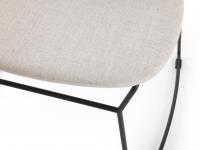 Detail der Sitzfläche des Stuhls Chloe, bezogen mit einem Stoff, der in einer Kontrastfarbe zum lackierten Metallgestell steht