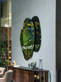 Der Spiegel bereichert Räume mit Reflexionen, die unterschiedliche Effekte zwischen den zentralen und seitlichen Platten in Rauchspiegel- oder Bronzeausführung erzeugen