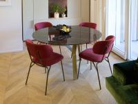 Tavolo rotondo in pietra ceramica lucida Noir Desir con sedie in velluto rosa fucsia.