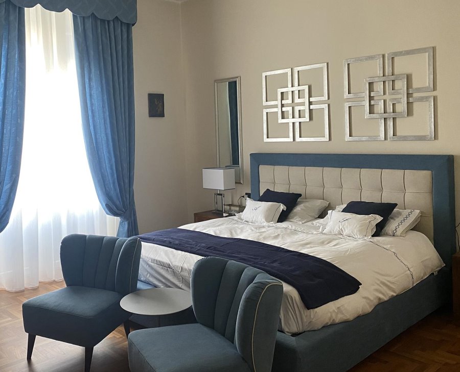 Camera con letto blu e bianco, pareti bianche, tende blu | Arabesque
