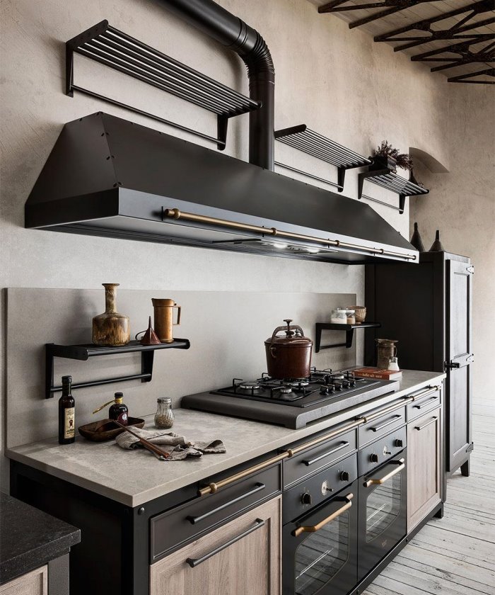 Dettaglio di una cucina in stile industrial con cappa a vista, fuochi ed elettrodomestici neri