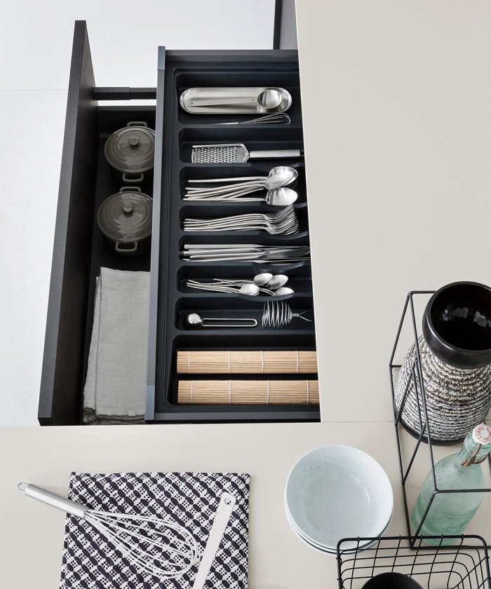 Dettaglio di un piano da cucina grigio chiaro con due cassetti neri aperti