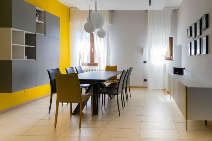 La sala da pranzo con tavolo, credenza e contenitori sospesi a parete