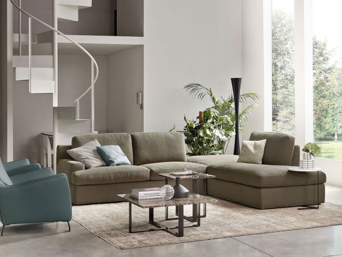 Marlow - divano componibile in un salotto con poltrone, tavolino centrale e scala a chiocciola posteriore