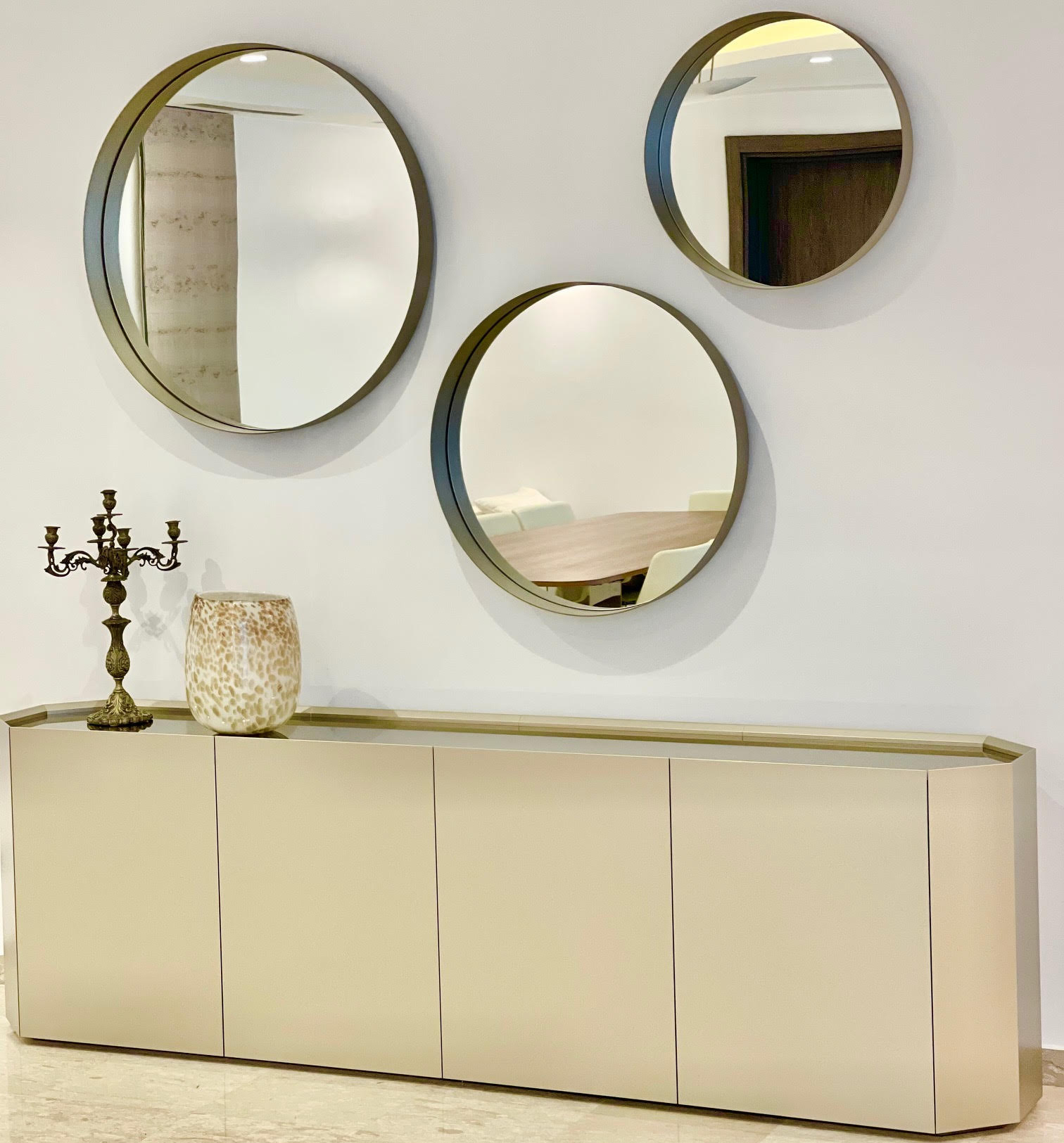 Parete arredata con credenza di design e specchi rotondi